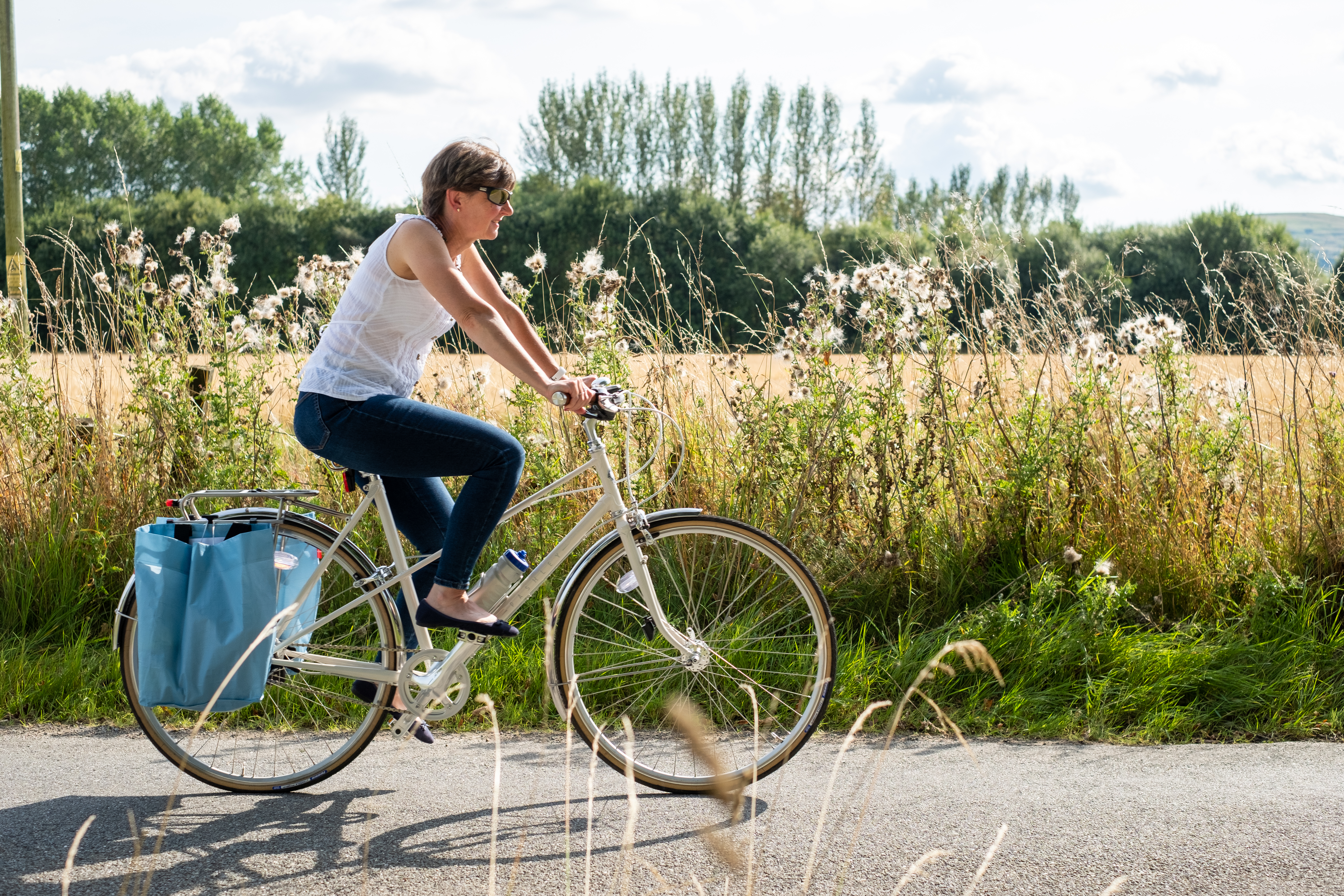 an older woman cycling on bike with flowers in the background